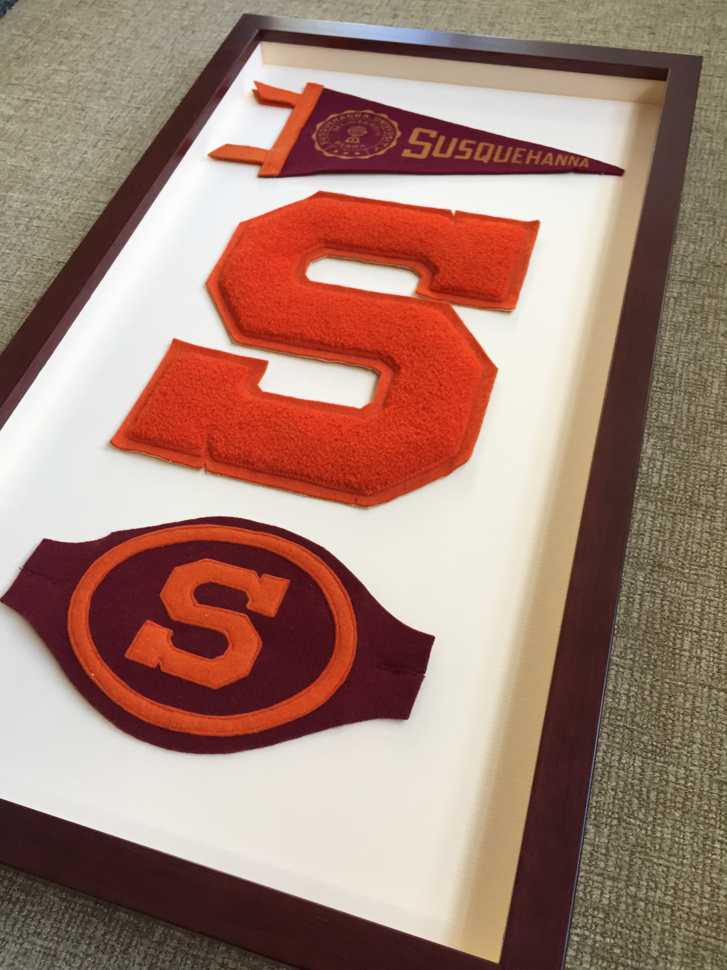 A custom framed shadowbox with college letters and vintage pennant.
