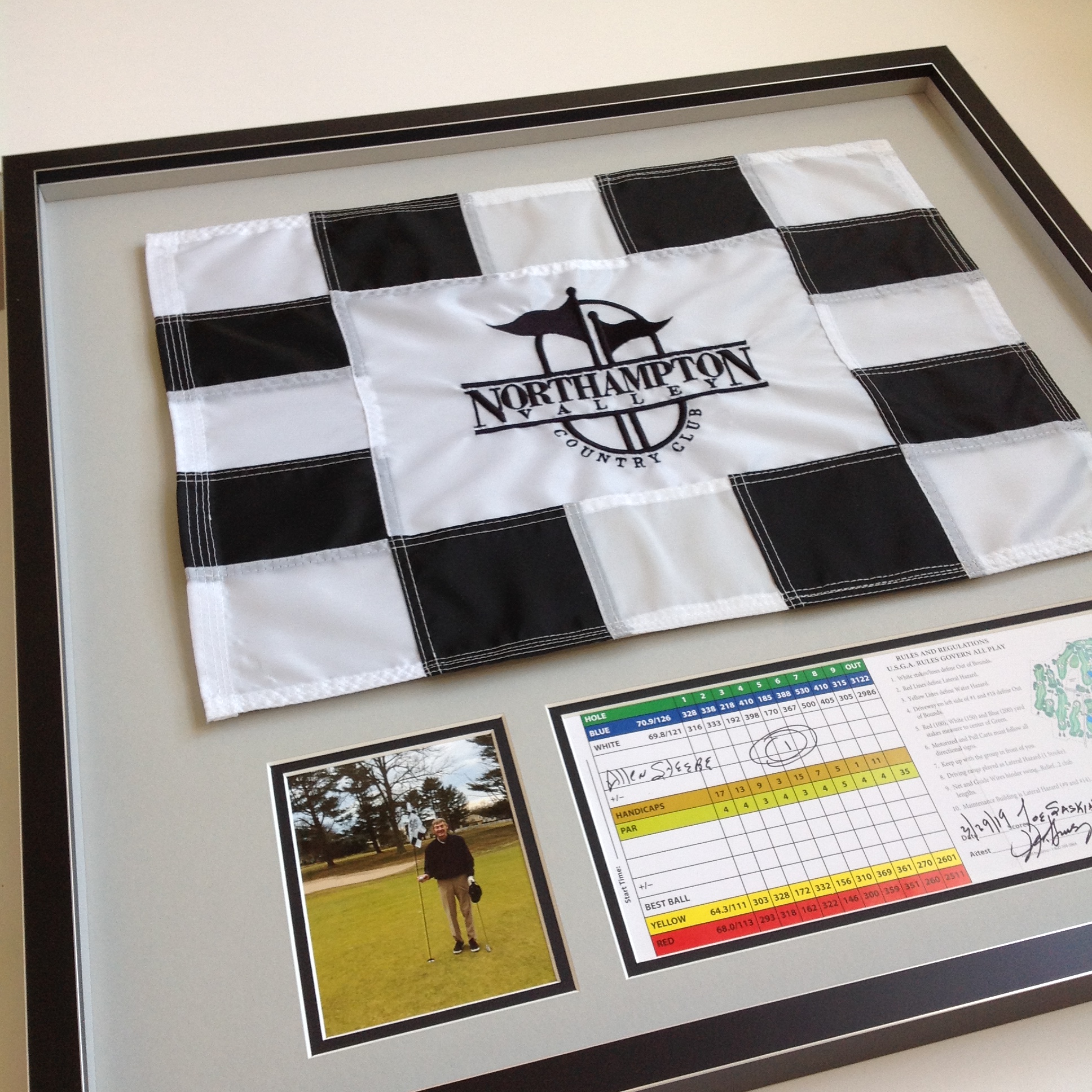 A custom framed golf flag, scorecard and photo celebrating a hole in one.